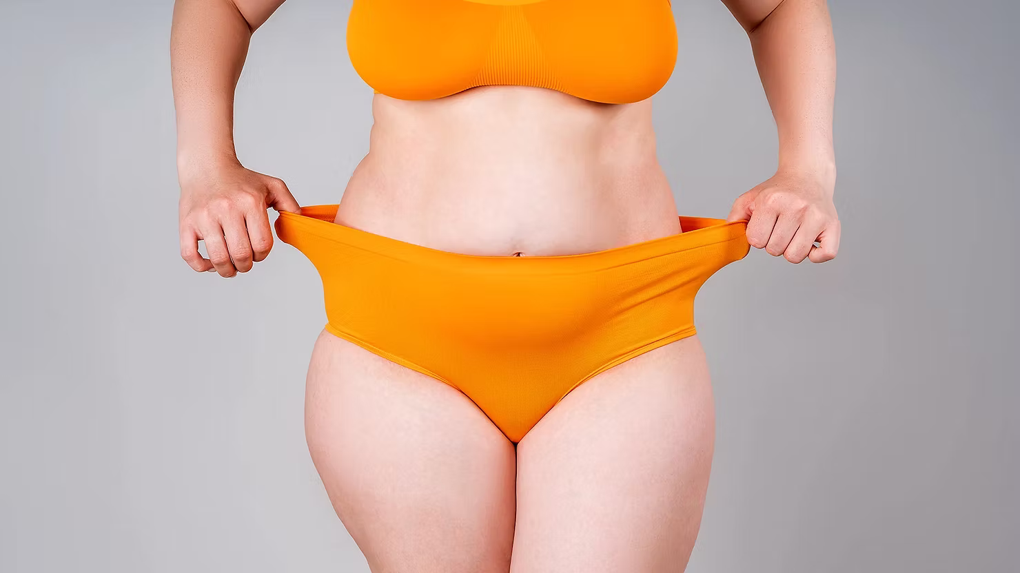 Woman in menopause stretching orange bottoms out.