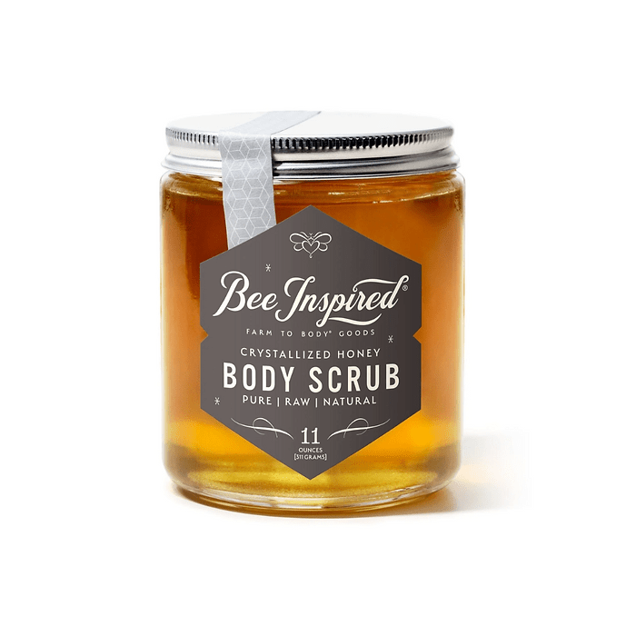 Bee Inspired crystallized honey body scrub in a clear jar with a silver lid. The label reads 'Bee Inspired Farm to Body Goods Crystallized Honey Body Scrub' and highlights its pure, raw, and natural ingredients. The jar contains 11 ounces of product.