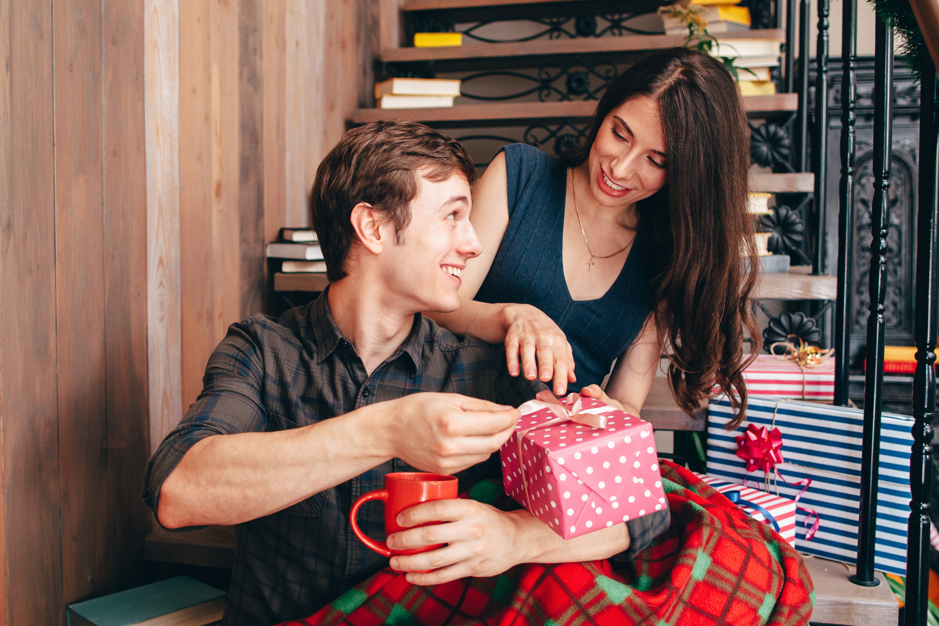 Smiling man presenting Christmas gift to happy woman. Xmas eve celebration at home. Happiness, joy, surprise, winter holiday, love concept