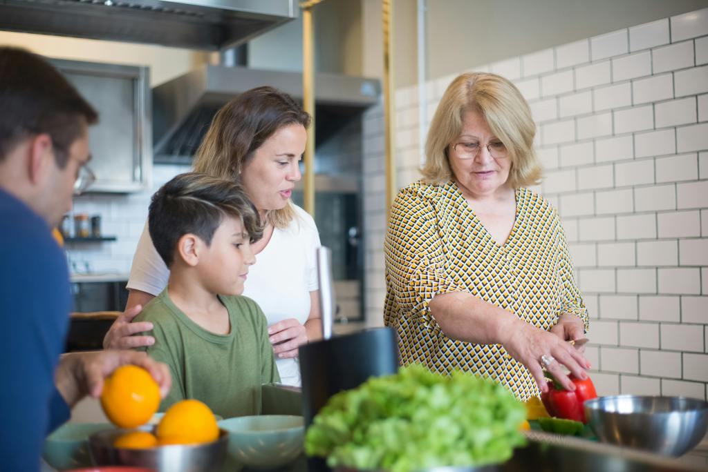 A family in the kitchen with a mom, child and grandma symbolizing the sandwich generation.