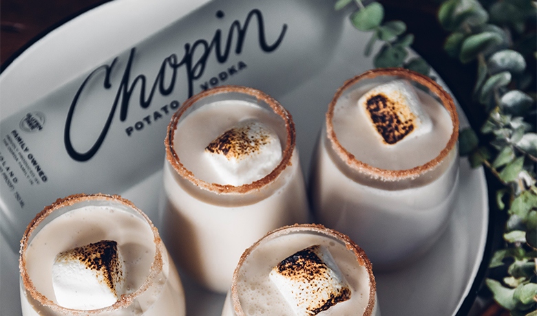 Four dessert shots with a toasted marshmallow on top, presented on a plate featuring the 'Chopin Vodka' logo.