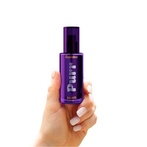 A hand holding a purple bottle of Purr Arousal Oil with a sleek design.