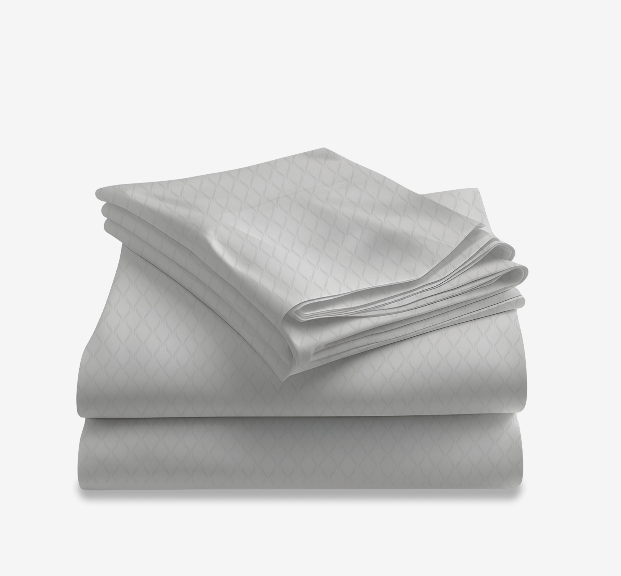 Temperature-Regulating cooling by Lusomé featuring two white sheets with a light grey pattern. 